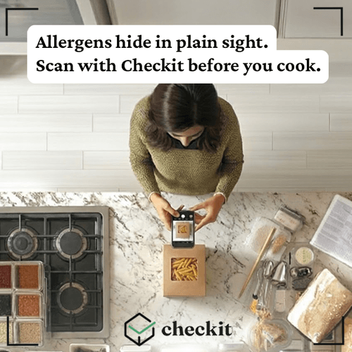 A woman is using a mobile app to scan a box of allergen information in a kitchen. The kitchen counter includes cooking utensils, a partially open cookbook, and various containers. The text on the image advises to scan with Checkit before cooking to h