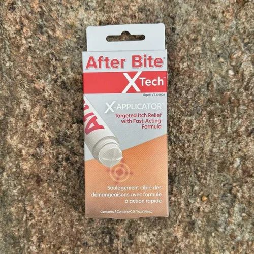 Box of After Bite X Tech liquid applicator for insect bites on a granite surface.